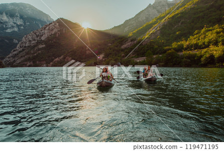 A group of friends enjoying fun and kayaking exploring the calm river, surrounding forest and large natural river canyons during an idyllic sunset. A group of friends enjoying fun and kayaking exploring the calm river, surrounding forest and large natural river canyons during an idyllic sunset. 119471195