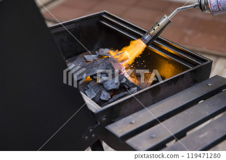 一名男子將木炭放入豪華露營設施的燒烤爐中並點燃。 119471280