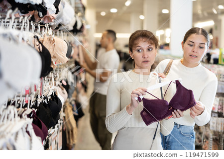 Two women choosing convenient bra in clothing store Two women choosing convenient bra in clothing store 119471599
