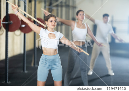 Young woman doing warm-up with stick Young woman doing warm-up with stick 119471610