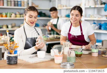 Two young women making pottery in workshop 119471615