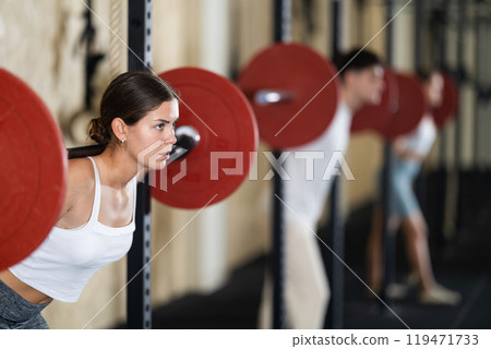 Young woman training with barbell in gym Young woman training with barbell in gym 119471733