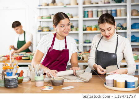 Two young women making pottery in workshop 119471757