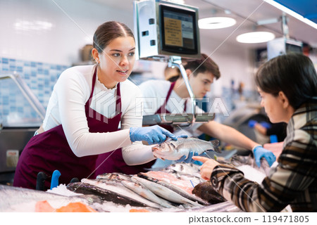 Positive saleswoman demonstrating seabass in fish store Positive saleswoman demonstrating seabass in fish store 119471805