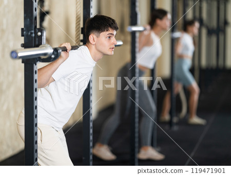 Young guy doing exercises with a barbell in gym 119471901