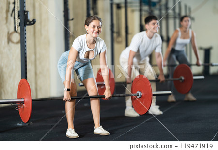 Young woman lifting barbell in gym Young woman lifting barbell in gym 119471919