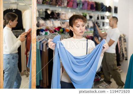 Adult woman choosing scarf in store 119471920