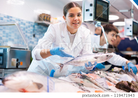Woman seller of fish advises buyer to buy atlantic bonito fresh fish Woman seller of fish advises buyer to buy atlantic bonito fresh fish 119471943