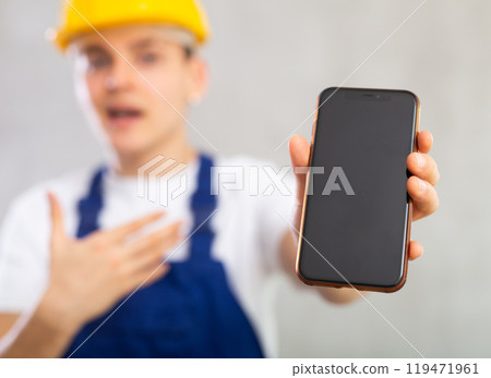 Enthusiastic young worker showing screen of mobile phone excitedly Enthusiastic young worker showing screen of mobile phone excitedly 119471961