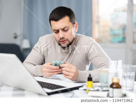 Young man looking for information about medicines on laptop Young man looking for information about medicines on laptop 119471962
