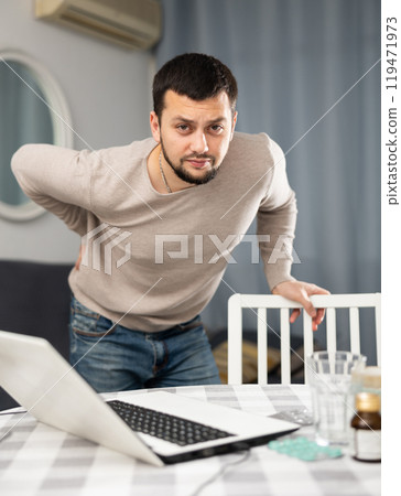 Young man suffering from low back pain at home 119471973