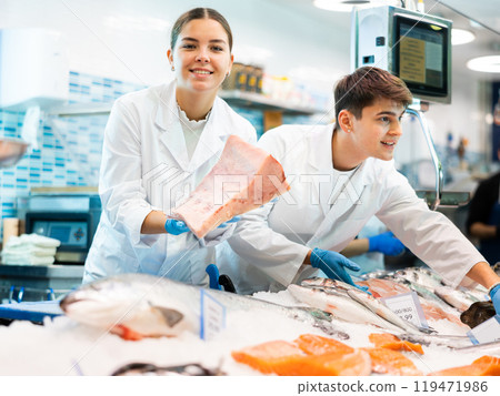 Responsive saleswoman demonstrating tuna in fish store Responsive saleswoman demonstrating tuna in fish store 119471986