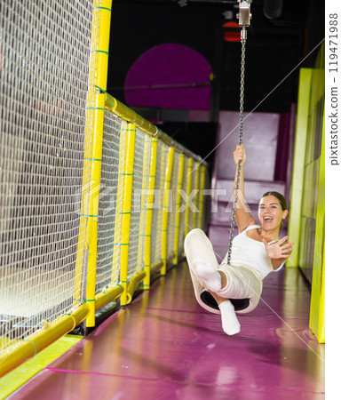 Laughing girl enjoying swing ride on zipline at indoor entertainment venue Laughing girl enjoying swing ride on zipline at indoor entertainment venue 119471988
