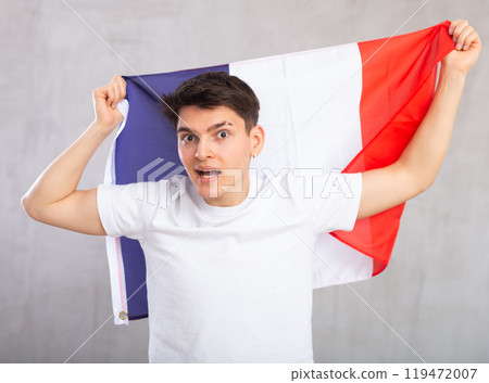 Energized,active male spectator holds national flag of France in hands and chants popular slogan Energized,active male spectator holds national flag of France in hands and chants popular slogan 119472007