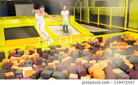 Happy athletes, man and girl, training to jump on trampolines at trampoline center 119472047