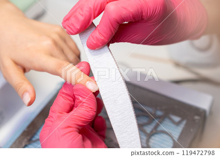 Professional manicure services with a nail file in a beauty salon. Professional manicure services with a nail file in a beauty salon. 119472798