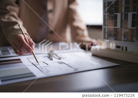 Female architect working and inspection architecture interior of construction project on blueprint 119473226