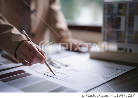 Female architect working and inspection architecture interior of construction project on blueprint 119473227