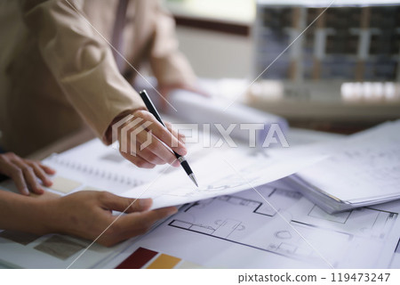 Two female architects discuss and brainstorm about interior designing building project on blueprint Two female architects discuss and brainstorm about interior designing building project on blueprint 119473247