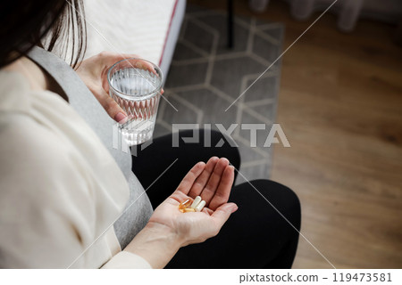 Pregnant woman holding glass of water, heap of pills in hand. Pregnancy health Pregnant woman holding glass of water, heap of pills in hand. Pregnancy health 119473581