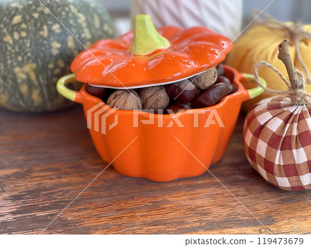 Pot of nuts, chestnuts and pumpkins on wooden old table. Composition for Halloween holiday. Autumn and harvest.  119473679
