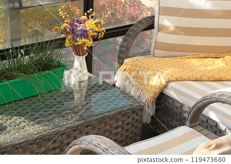 Wicker patio furniture and dry flowers on sunny autumn day in backyard. Garden furniture for relaxing.  119473680