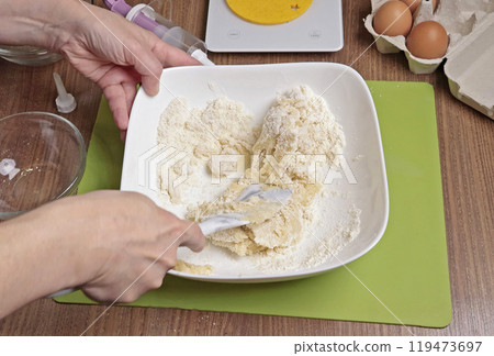 Process of making dough. Woman mixed powdered sugar, almond flour and egg white with silicone spatula in bowl. Baking macarons at home. Hands close-up. Process of making dough. Woman mixed powdered sugar, almond flour and egg white with silicone spatula in bowl. Baking macarons at home. Hands close-up. 119473697