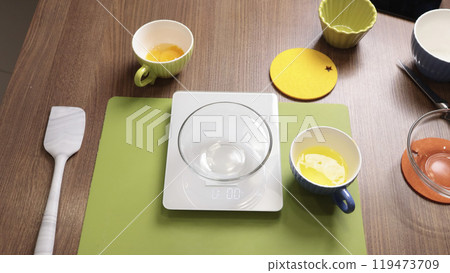 Process of preparing scales and dishes for dough preparation. Objects on wooden table. Process of preparing scales and dishes for dough preparation. Objects on wooden table. 119473709
