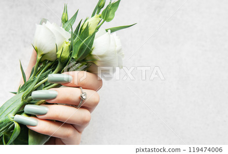A hand holding a delicate bouquet of white flowers against a soft textured background A hand holding a delicate bouquet of white flowers against a soft textured background 119474006