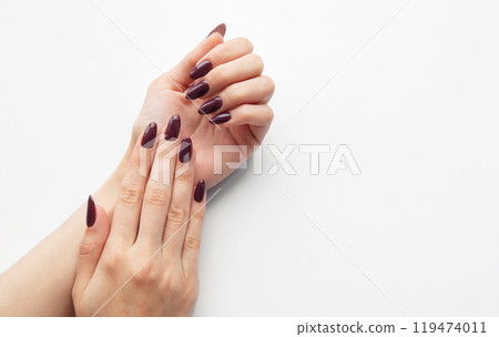 Elegant hands displaying deep burgundy manicure on a clean white background  119474011