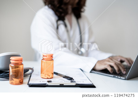 Female doctor holding a medicine bottle is checking the quality of medicine for any side effects the patient or not and recording patient information at the hospital. medical and health care concept Female doctor holding a medicine bottle is checking the quality of medicine for any side effects the patient or not and recording patient information at the hospital. medical and health care concept 119474275