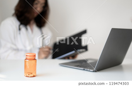 Female doctor holding a medicine bottle is checking the quality of medicine for any side effects the patient or not and recording patient information at the hospital. medical and health care concept Female doctor holding a medicine bottle is checking the quality of medicine for any side effects the patient or not and recording patient information at the hospital. medical and health care concept 119474303