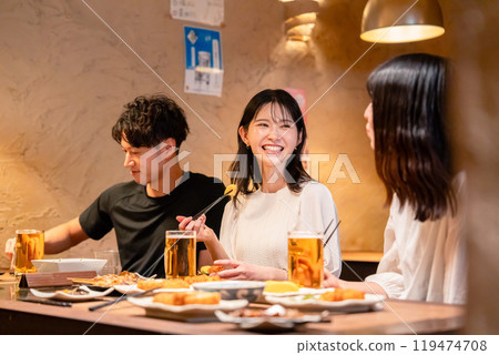 Young men and women drinking alcohol at an izakaya 119474708