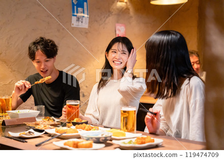 Young men and women drinking alcohol at an izakaya 119474709