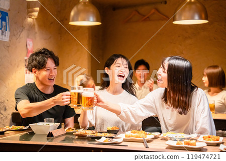 Young men and women drinking alcohol at an izakaya 119474721
