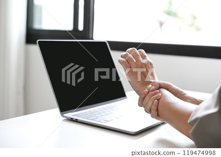 Woman hand with wrist pain numbness and pain in the palm of the hand has pain and tingling in the nerve endings This is a side effect of sitting and working for a long time on a laptop at the office Woman hand with wrist pain numbness and pain in the palm of the hand has pain and tingling in the nerve endings This is a side effect of sitting and working for a long time on a laptop at the office 119474998