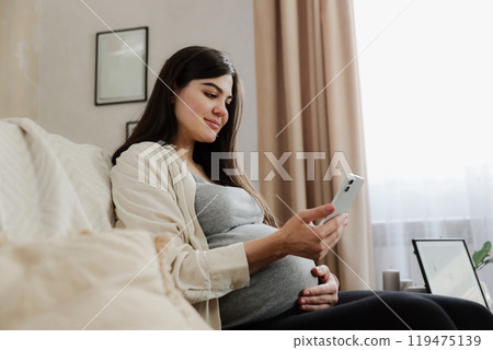 Young pregnant woman with baby belly using her mobile cell phone 119475139