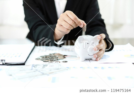 Woman's hand. putting coins in the piggy bank with coins, saving money with coins, stepping into a successful growing business, and saving for thought in retirement. Retirement savings concept 119475164