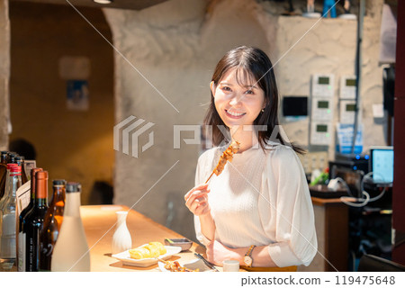 一個女人獨自坐在櫃檯座位上吃烤雞肉串 一個女人獨自坐在櫃檯座位上吃烤雞肉串 119475648