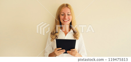 Happy smiling young woman employee with digital tablet computer or folder with documents in office 119475813