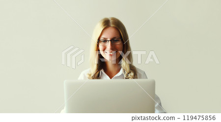 Happy woman working with laptop sitting at desk in office or home 119475856
