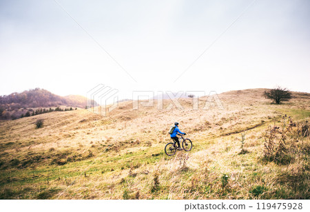 Cyclist far in the middle of beautiful nature during early autumn morning. Concept of healthy lifestyle. Cyclist far in the middle of beautiful nature during early autumn morning. Concept of healthy lifestyle. 119475928