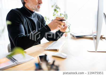 Homeoffice for handsome man. Man drinking coffee in the morning, working on computer from home. Telecommuting. 119475951