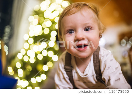 Little baby boy in Christmas home. Cute boy is surprised and amazed by the Christmas decorations. Little baby boy in Christmas home. Cute boy is surprised and amazed by the Christmas decorations. 119475960