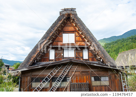Shirakawa village, Gifu, Japan. A traditional wooden house featuring a steep roof adorned with thatch Shirakawa village, Gifu, Japan. A traditional wooden house featuring a steep roof adorned with thatch 119476457