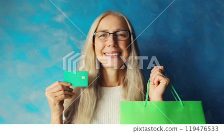 Portrait of happy smiling middle aged woman holding plastic credit bank card with shopping bags 119476533