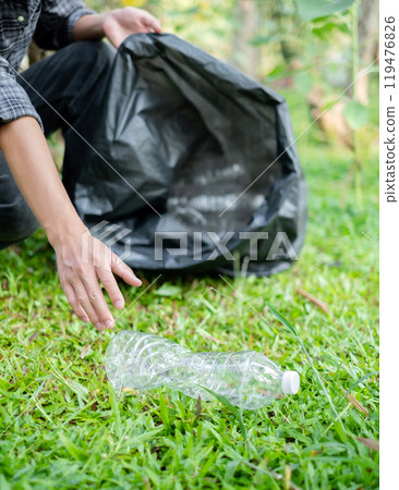 Man's hands pick up plastic bottles, put garbage in black garbage bags to clean up at parks, avoid pollution, be friendly to the environment and ecosystem Man's hands pick up plastic bottles, put garbage in black garbage bags to clean up at parks, avoid pollution, be friendly to the environment and ecosystem 119476826