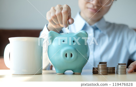 A young woman teaches how to put coins in a piggy bank start a growing business for success and save for retirement concept 119476828