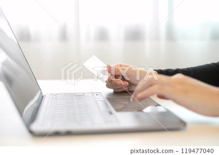 Asian girl shopping online holding credit and using laptop enter their card number in the mobile phone app to purchase and payment in internet store 119477040
