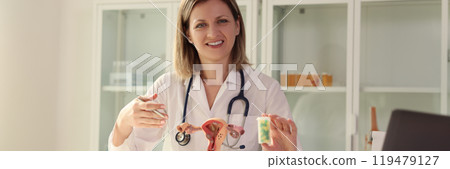 Lady gynecologist holds bottle of pills looking in camera 119479127